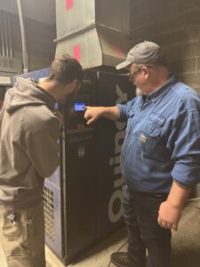 Service technician teaching customer about their Quincy Rotary Screw Air Compressor.